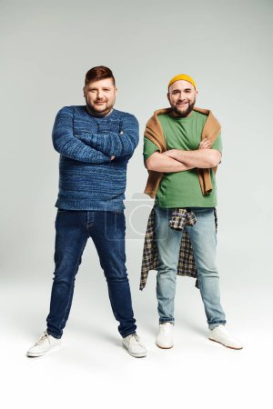 Two men with crossed arms stand confidently next to each other.