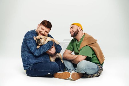 Ein schwules Paar genießt mit seiner Französischen Bulldogge einen friedlichen Moment auf dem Boden.
