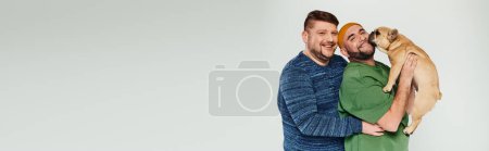 Photo for A man tenderly holds a French bulldog in his arms. - Royalty Free Image