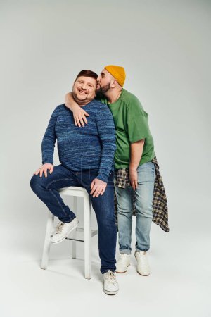 Two men sitting on a stool cheerfully.