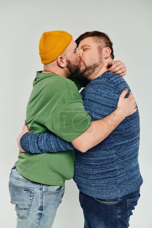 Dos hombres besándose amorosamente sobre fondo blanco.