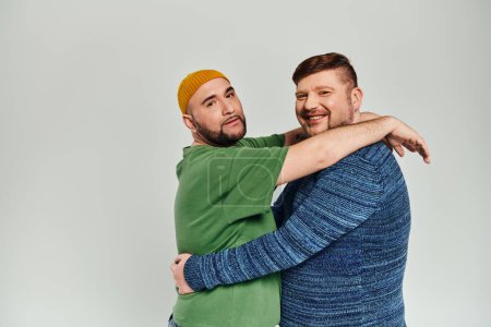 Two men hugging warmly in front of a white backdrop.