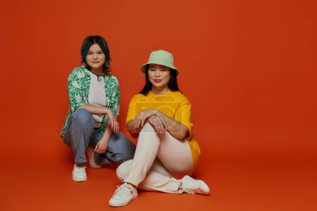 An Asian mother and her teenage daughter sitting together in a studio, sharing a moment of connection and closeness.