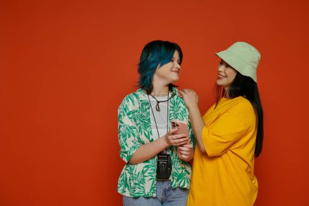 Photo for An Asian mother and her teenage daughter stand side by side in front of a vibrant wall in a studio setting. - Royalty Free Image