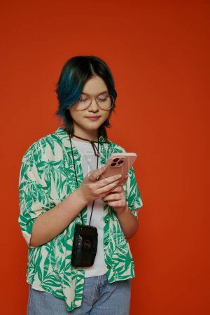 An Asian mother and her teenage daughter, both with striking blue hair, immersed in their cell phones in a vibrant studio.