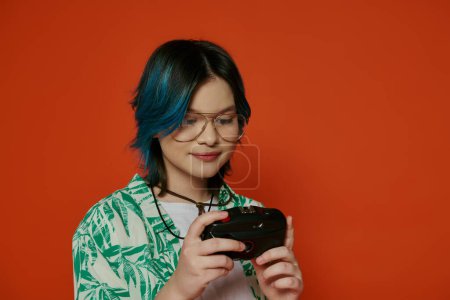 Foto de Una adolescente con el pelo azul vivo en un entorno de estudio, sosteniendo una cámara con un fondo naranja. - Imagen libre de derechos