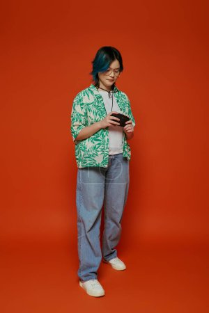 Téléchargez les photos : Asiatique adolescent fille debout sereinement devant une dynamique orange toile de fond. - en image libre de droit