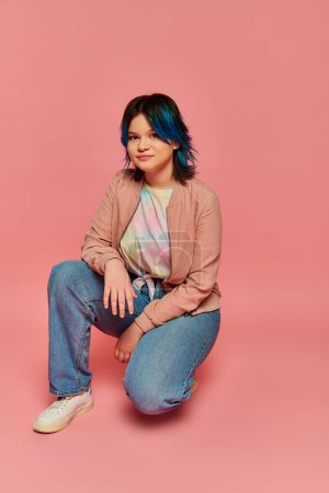 Téléchargez les photos : A stunning woman with blue hair sits gracefully against a vibrant pink background in a serene and artistic setting. - en image libre de droit