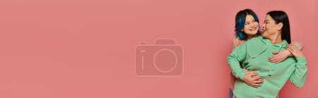 Téléchargez les photos : Mère asiatique et fille adolescente se tiennent côte à côte, portant des vêtements décontractés, dans un studio avec un fond rose. - en image libre de droit