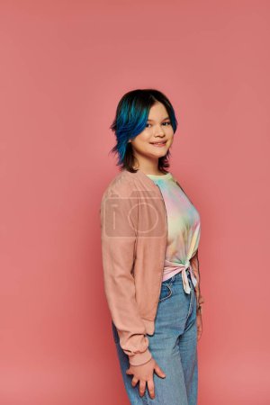 Foto de Asiática chica con el pelo azul de pie con estilo delante de una audaz pared de color rosa en un entorno de estudio. - Imagen libre de derechos