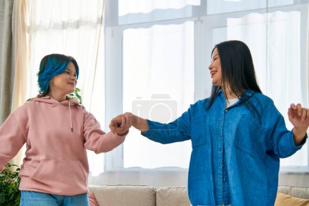 An Asian mother and her teenage daughter stand closely next to each other in casual wear, sharing a moment of connection.