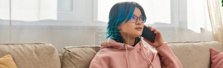 Téléchargez les photos : Une fille asiatique aux cheveux bleus s'assoit sur un canapé, parlant sur un téléphone portable - en image libre de droit