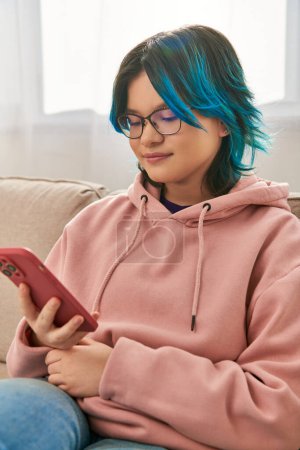 Téléchargez les photos : Une fille asiatique cheveux bleus, assis confortablement sur un canapé, profitant d'un moment de connexion - en image libre de droit