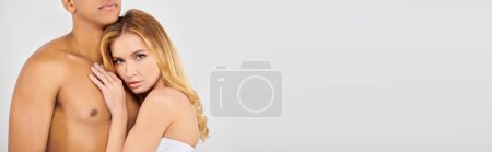 Chic man and woman pose together on white backdrop.