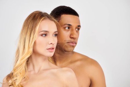 Trendy diverse couple posing elegantly in front of a white backdrop.