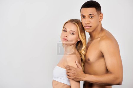 attractive man and woman lovingly pose against white backdrop during skin care routine.