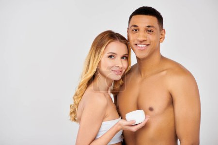 Un couple élégant pose ensemble, tenant une tasse de crème, montrant leur amour pour les soins de la peau.