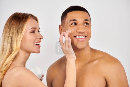 Photo for Man and woman lovingly apply face cream together. - Royalty Free Image