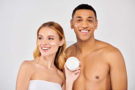Photo for A couple enjoying a skincare moment with facial cream. - Royalty Free Image