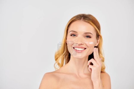Jeune femme appliquant de la crème visage pendant la routine des soins de la peau.