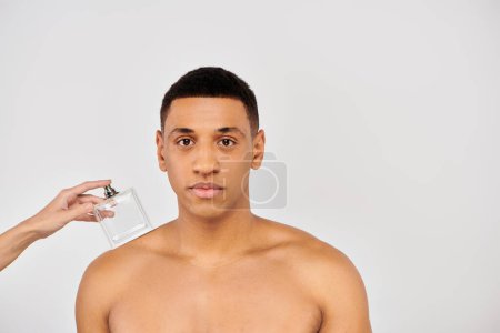 Foto de Mano de mujer con perfume cerca de hombre afroamericano. - Imagen libre de derechos