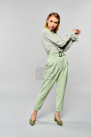 Foto de Una mujer elegante con pantalones verdes posando para una cámara. - Imagen libre de derechos