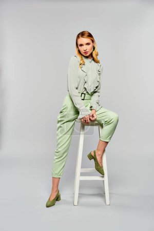 Foto de A woman with green pants sitting on a stool. - Imagen libre de derechos