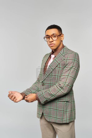 Téléchargez les photos : Un homme à lunettes pose avec confiance dans un élégant blazer à carreaux. - en image libre de droit