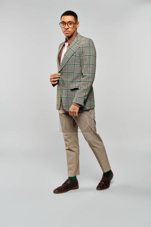 Ein modischer Mann im grün karierten Blazer posiert für ein Foto.