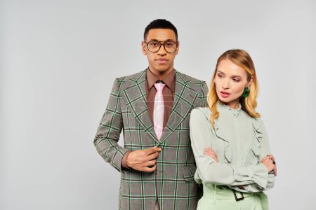 Photo for A stylish man and woman in suits strike a pose against a white backdrop. - Royalty Free Image