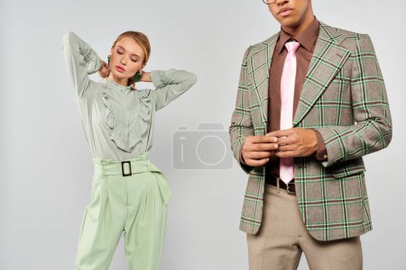 Photo for A chic man and woman in plaid jackets and green pants pose together. - Royalty Free Image