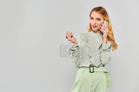 A young woman in a green blouse chats on the telephone.