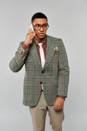 Stylish man in checkered blazer talking on cell phone.