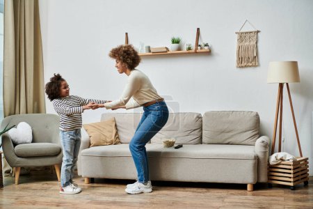 An African American mother and her kid are dancing joyfully in their living room, bonding through music and movement.