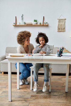 Foto de Madre e hija afroamericanas comparten un momento acogedor en una mesa en una sala de estar, irradiando felicidad y amor. - Imagen libre de derechos