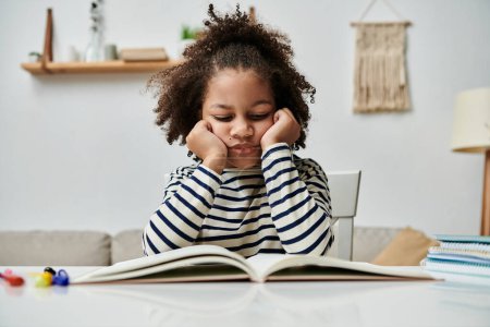 bored African American girl engrossed in a book, sitting at a table