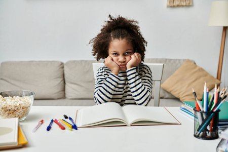 Foto de Una niña absorta en un libro en una mesa, aburrida - Imagen libre de derechos
