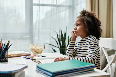 Photo for A little girl engrossed in her dreams, sitting at a desk - Royalty Free Image