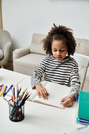 Una niña de ascendencia afroamericana se sienta en una mesa, centrada en su cuaderno y sus coloridos lápices, dedicada a actividades creativas.