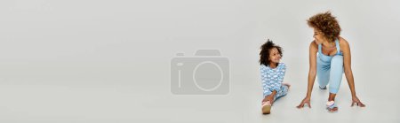 Photo for A happy African American mother and daughter in pajamas posing in front of a white background. - Royalty Free Image