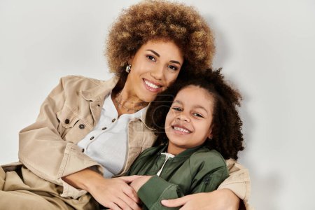 Photo for Curly African American mother and daughter in stylish clothes posing together on a grey background. - Royalty Free Image