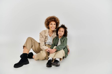 Stylish African American mother and daughter sitting on the floor, sharing a peaceful and loving moment together.