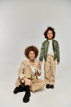 Photo for A stylish African American mother and daughter with curly hair posing together on a grey background. - Royalty Free Image