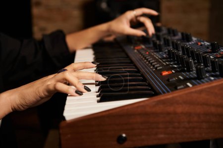 A talented woman effortlessly plays a synthesizer in a recording studio, creating the perfect harmony for her music band rehearsal.