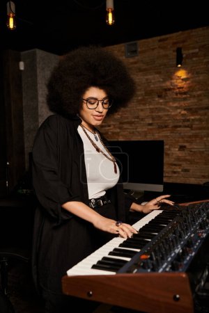 A talented woman with an afro hairstyle plays a keyboard during a music band rehearsal in a recording studio.