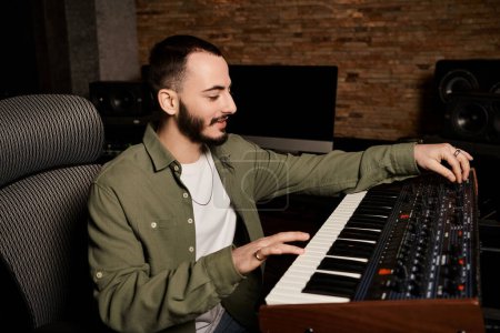 Hombre talentoso explora las posibilidades sonoras en el teclado electrónico durante el ensayo de la banda de música en un estudio de grabación profesional.