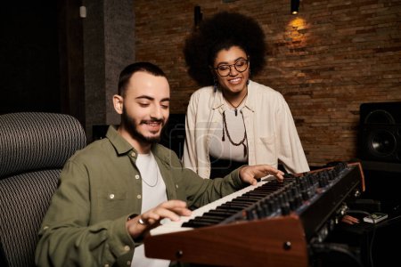 Un hombre y una mujer, músicos, colaborando en un ensayo de la banda de música en un estudio de grabación profesional.