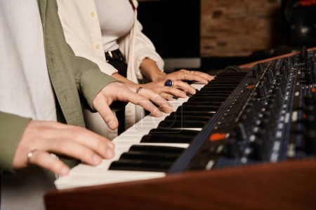Zwei Personen, die Musik auf einem Keyboard in einem Tonstudio für eine Bandprobe aufführen.