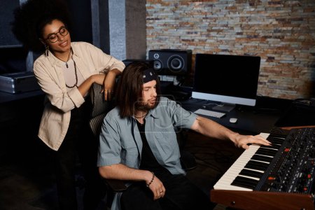 Foto de Un hombre y una mujer colaboran en la música en un estudio de grabación mientras ensayan para su banda. - Imagen libre de derechos