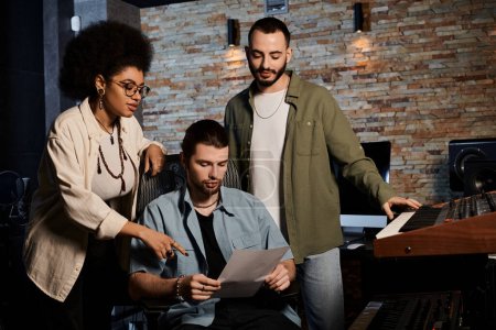 Three individuals in a recording studio scrutinizing a sheet of music.